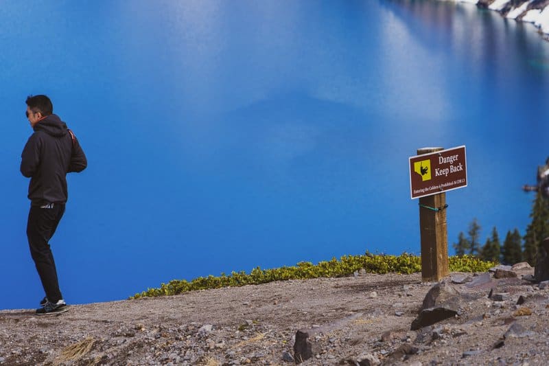In this picture there’s a sign and a person making a really poor decision. This guy ignored the signs at Crater Lake in Oregon and then nearly fell as he tried to get closer to the edge to take photos. That shortly after a couple nearly fell trying to take a selfie. I’m amazed more people don’t fall to their deaths at crater lake... the guy in this picture was caught and then chewed out royally by a park ranger. 